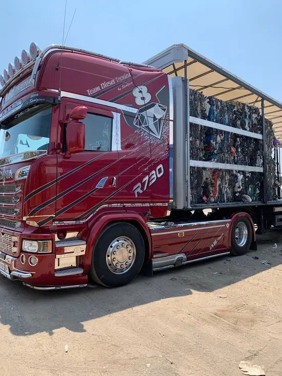 Camion semirimorchio rosso con un grande rimorchio parcheggiato all'aperto sotto il sole.