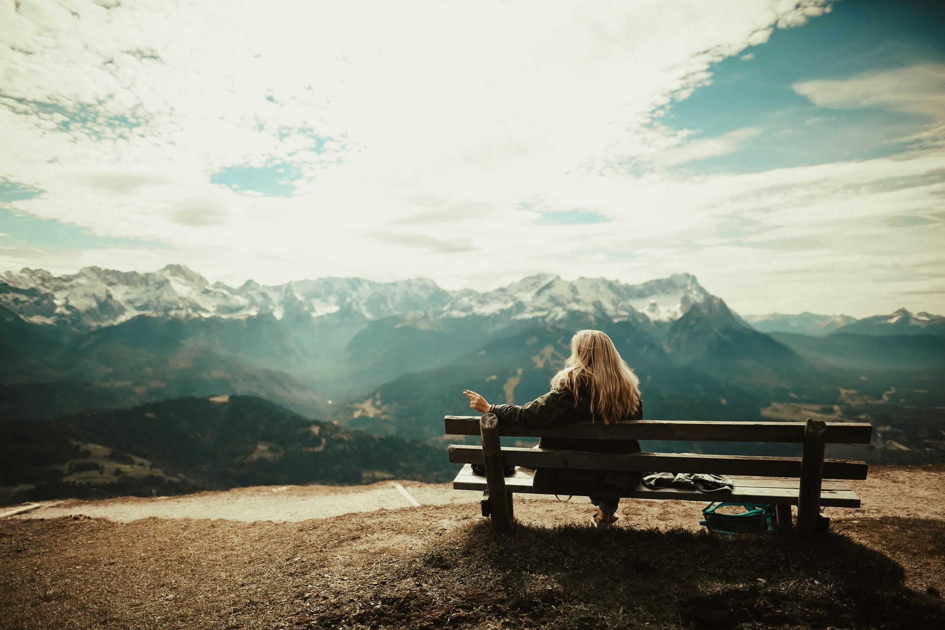 Girl setting on bench looking over mountain ranges