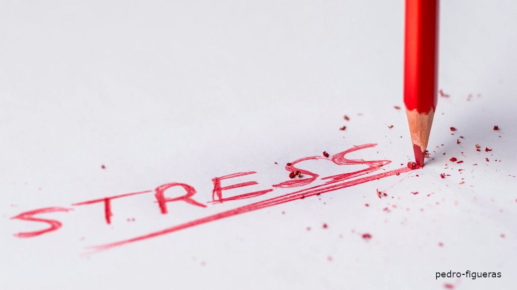 Red colour pencil writing the word stress in caps.