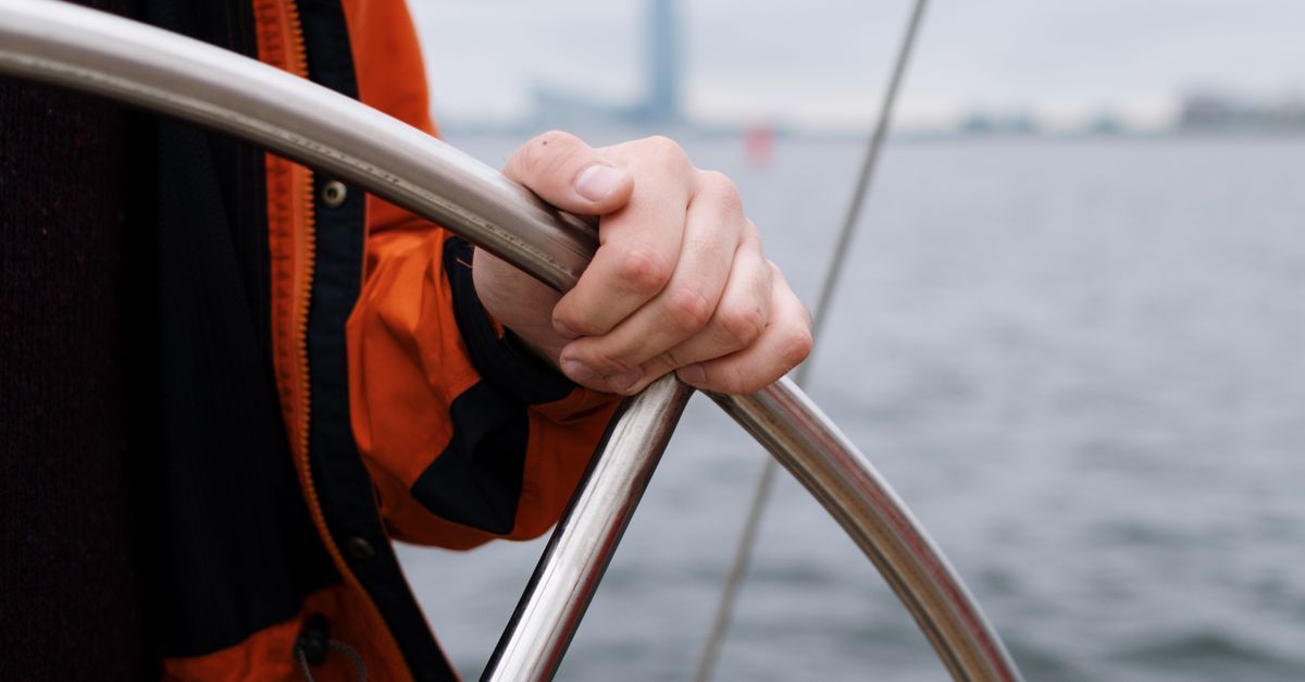 A person steering a small boat towards the horizon, representing choosing direction