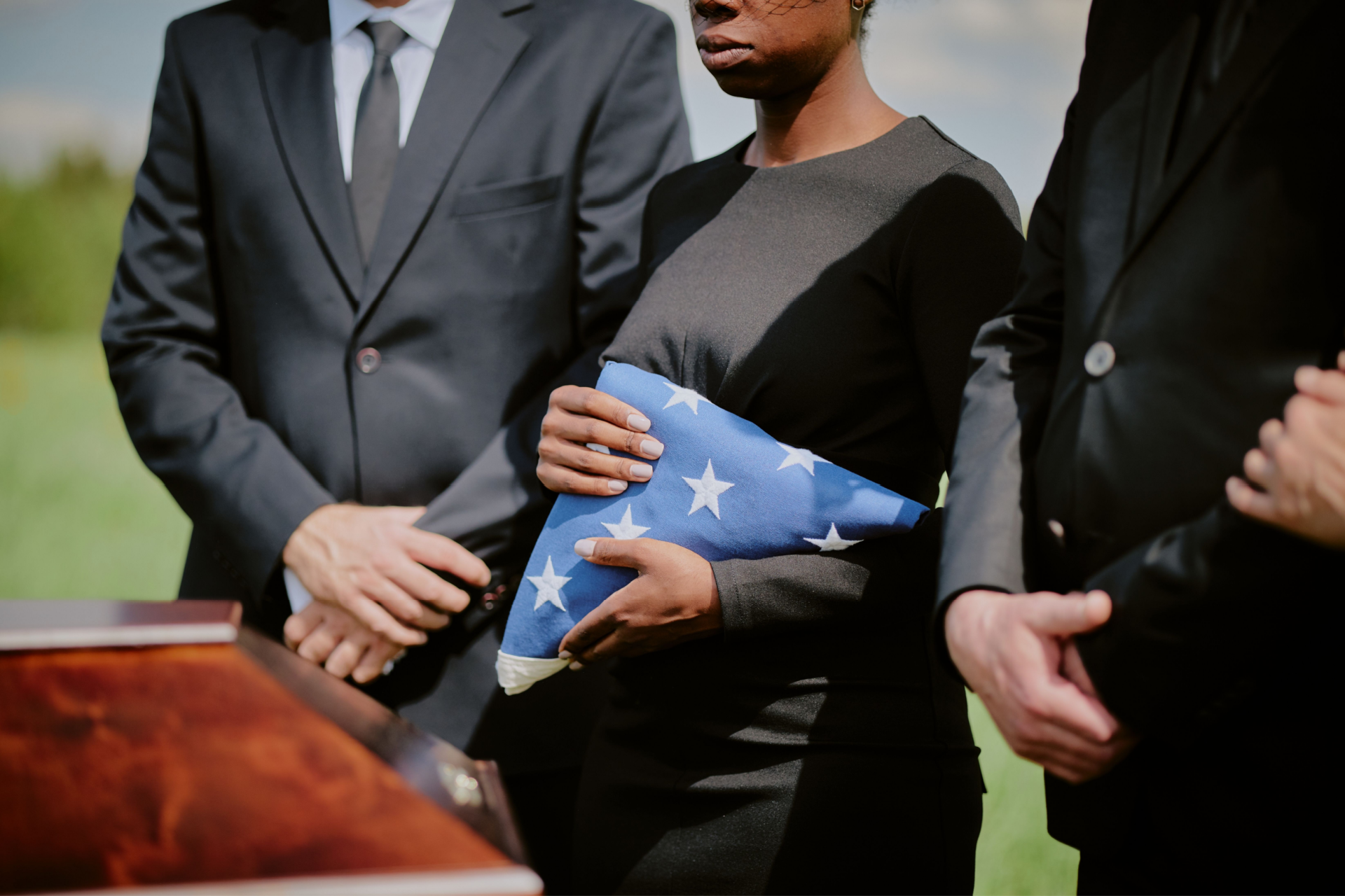 A woman is putting her hand on an American flag at a funeral.