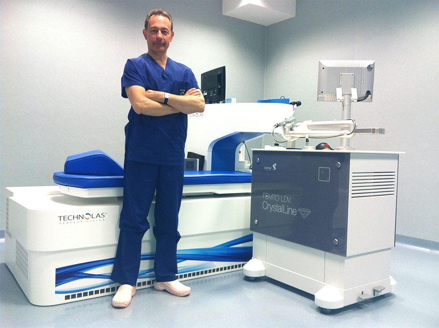 Un uomo in camice blu è in piedi accanto a uno scanner per immagini mediche in una stanza clinica.