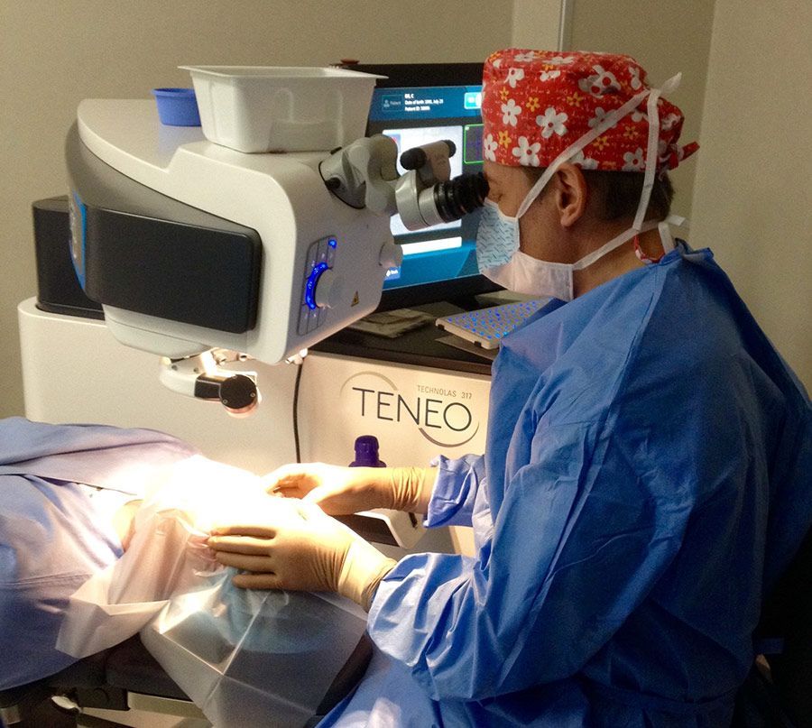 Dentista con tuta protettiva blu che utilizza un microscopio dentale Teneo durante una procedura.