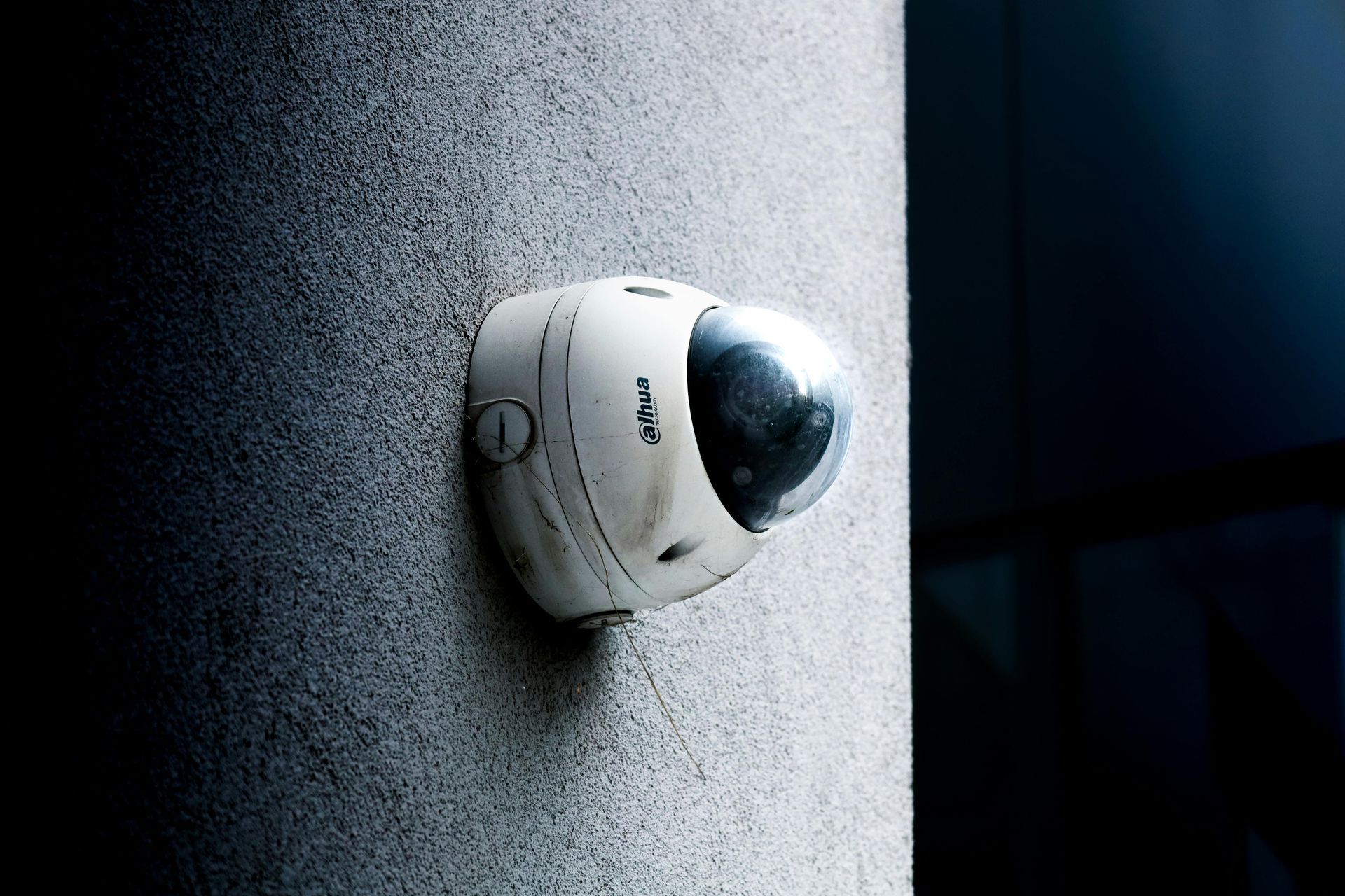 White security camera mounted on a textured wall, angled toward the right.