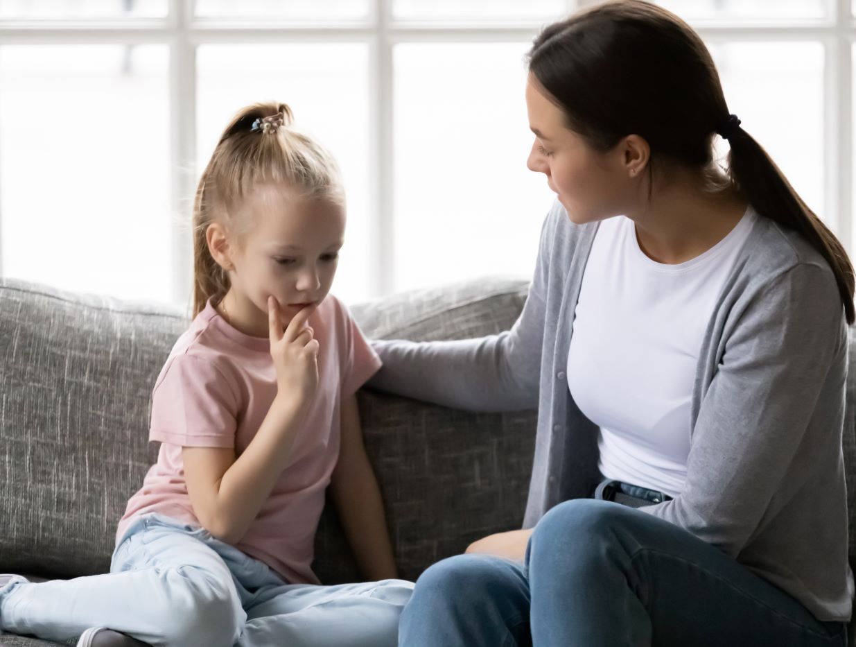Adult comforting a child on a couch in a bright living room