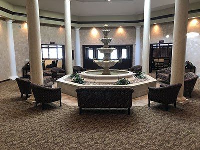 there is a fountain in the middle of the room with chairs and a couch.