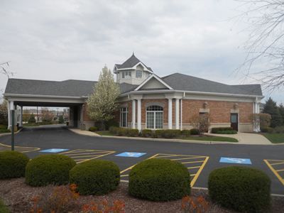 a large brick building with a gray roof and a parking lot in front of it.