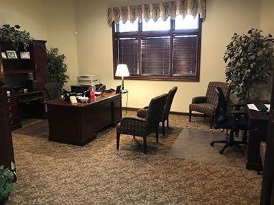a large office with a desk, chairs, and a window.