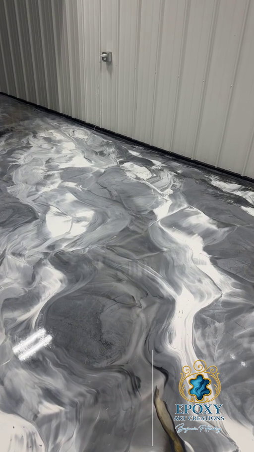 Epoxy floor with marbled grey and white design. Shows a wall with an electrical outlet in an indoor setting.
