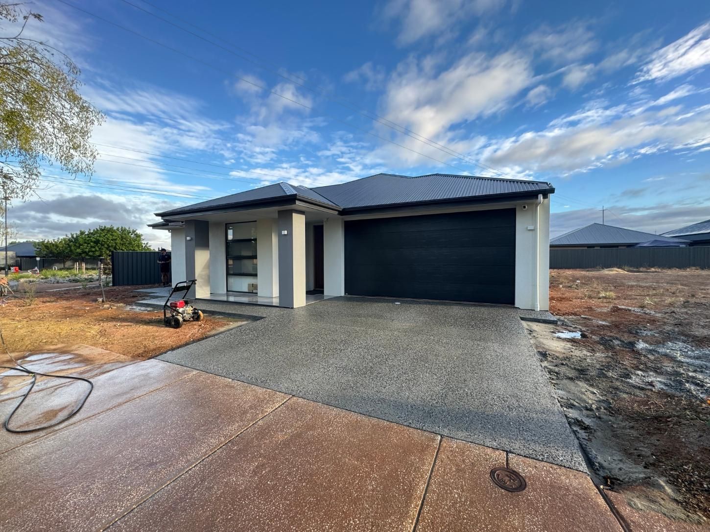 New modern house with grey driveway and garage, blue sky.