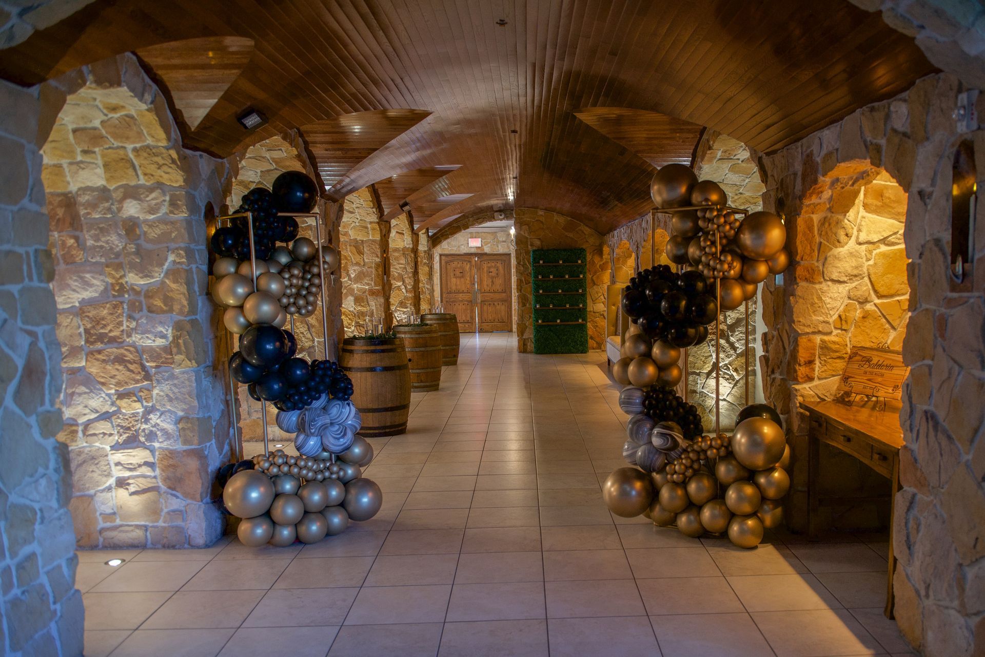 A hallway filled with balloons and barrels in a wine cellar.