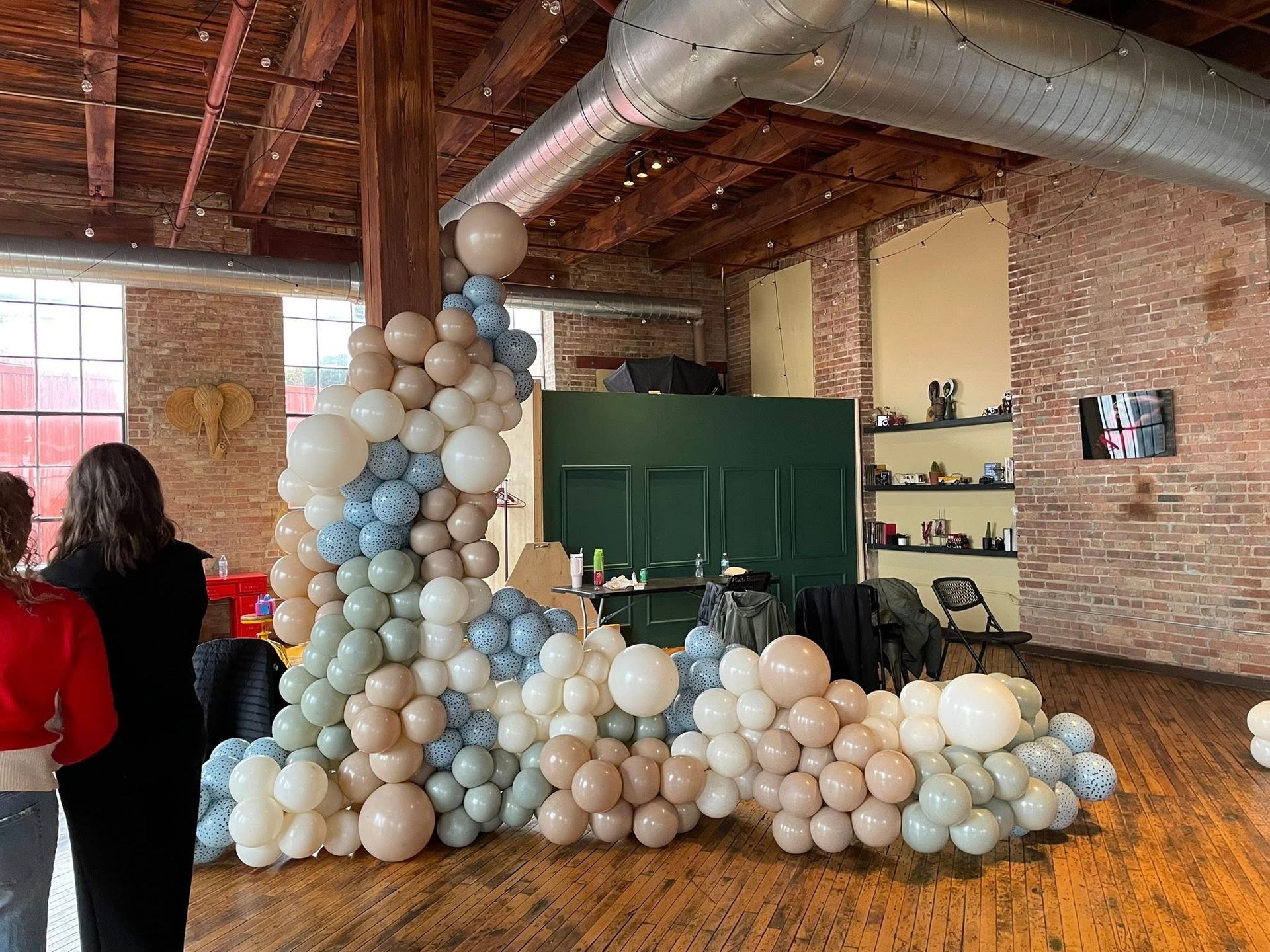 A bunch of balloons are sitting on a wooden floor in a room.