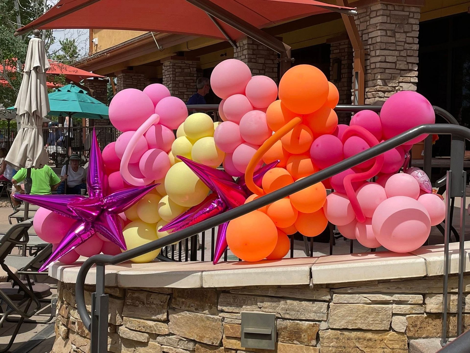 A bunch of balloons are sitting on top of a stone wall.