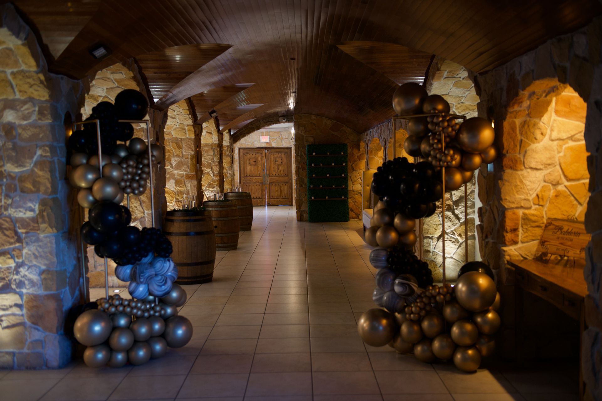 A hallway filled with balloons and barrels in a wine cellar.