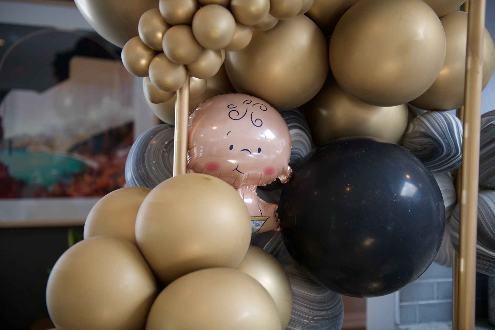 A bunch of gold and black balloons are hanging from the ceiling.