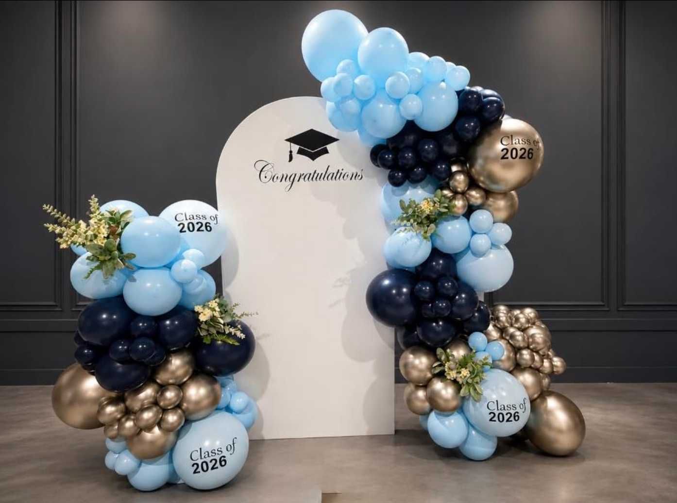 A bunch of balloons are stacked on top of each other in front of a wooden fence.