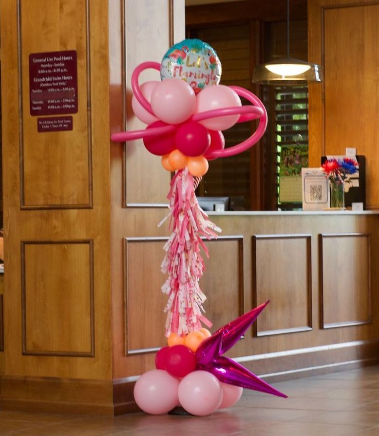 A pink and red balloon display with a happy birthday balloon