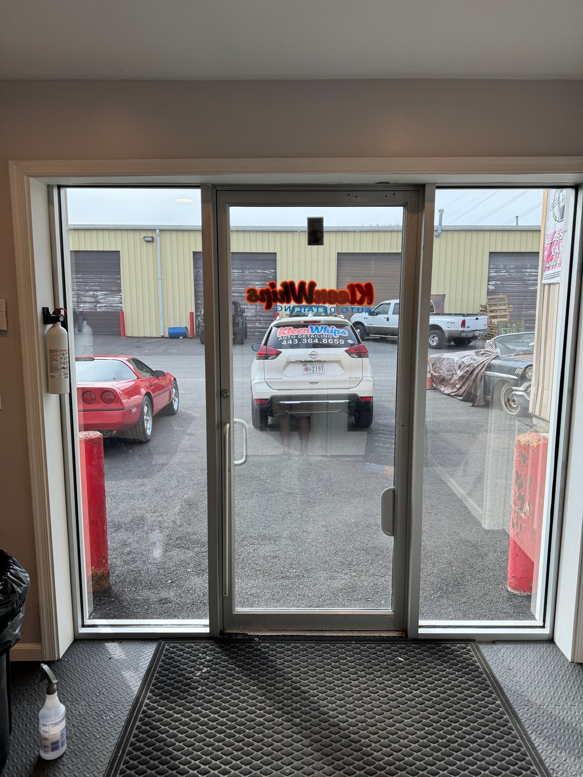 A car is parked in front of a glass door.