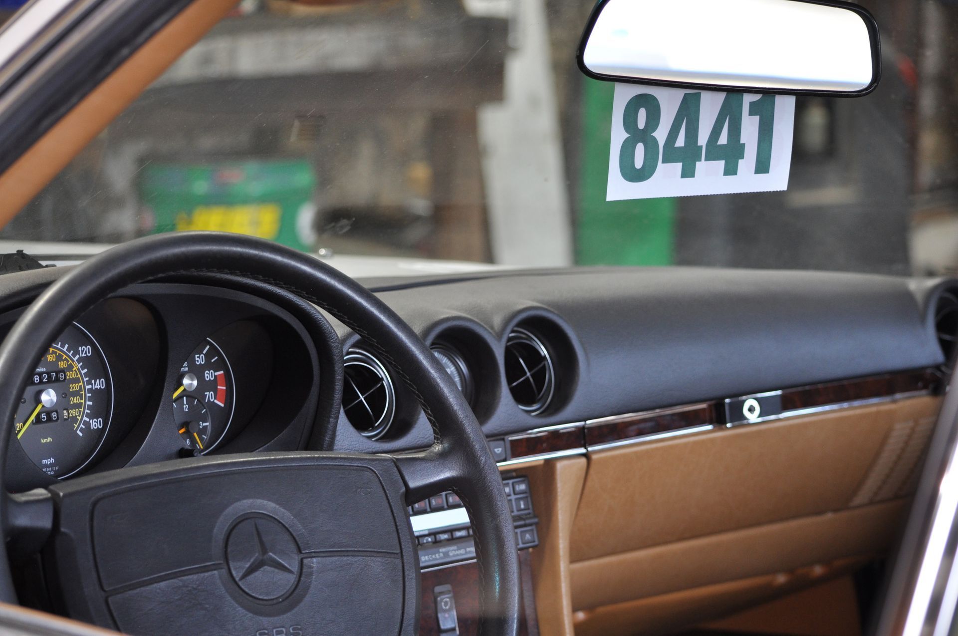 Mercedes-Benz dashboard and steering wheel with tan interior, seen from the driver’s seat, garage background.