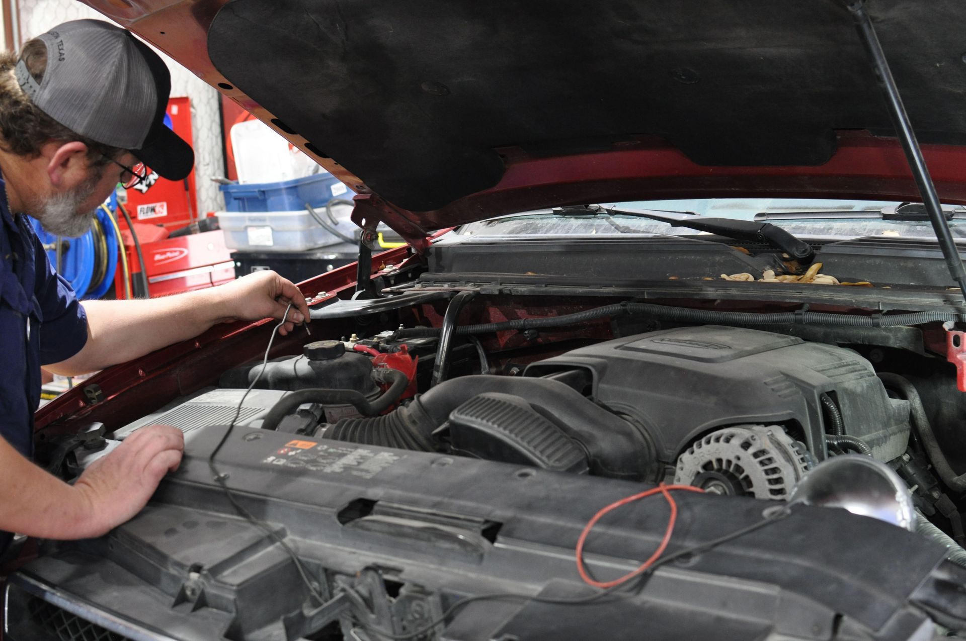 Mechanic inspecting engine bay with open hood and diagnostic tools in a garage