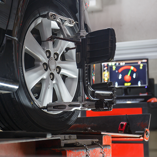 Car wheel on alignment machine with sensor and monitor displaying alignment data