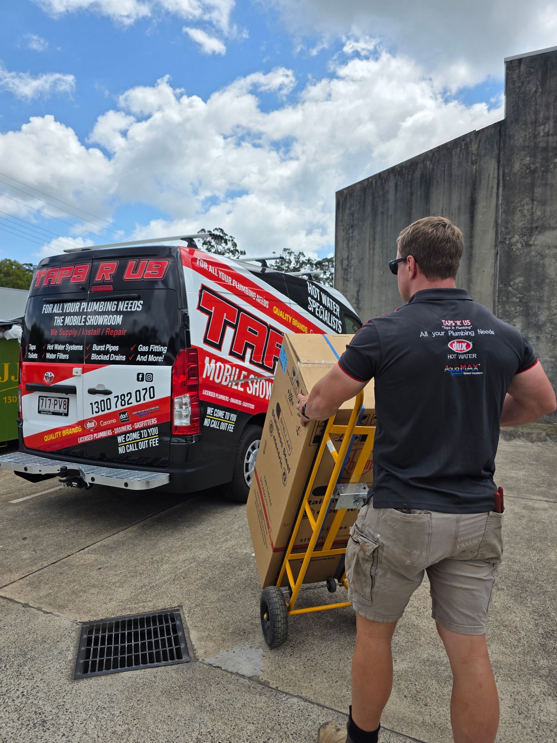 Man Pushing a Yellow Pallet Jack Beside a Red-And-White Racing Truck in A Parking Lot — Taps 'R' Us in Kunda Park, QLD