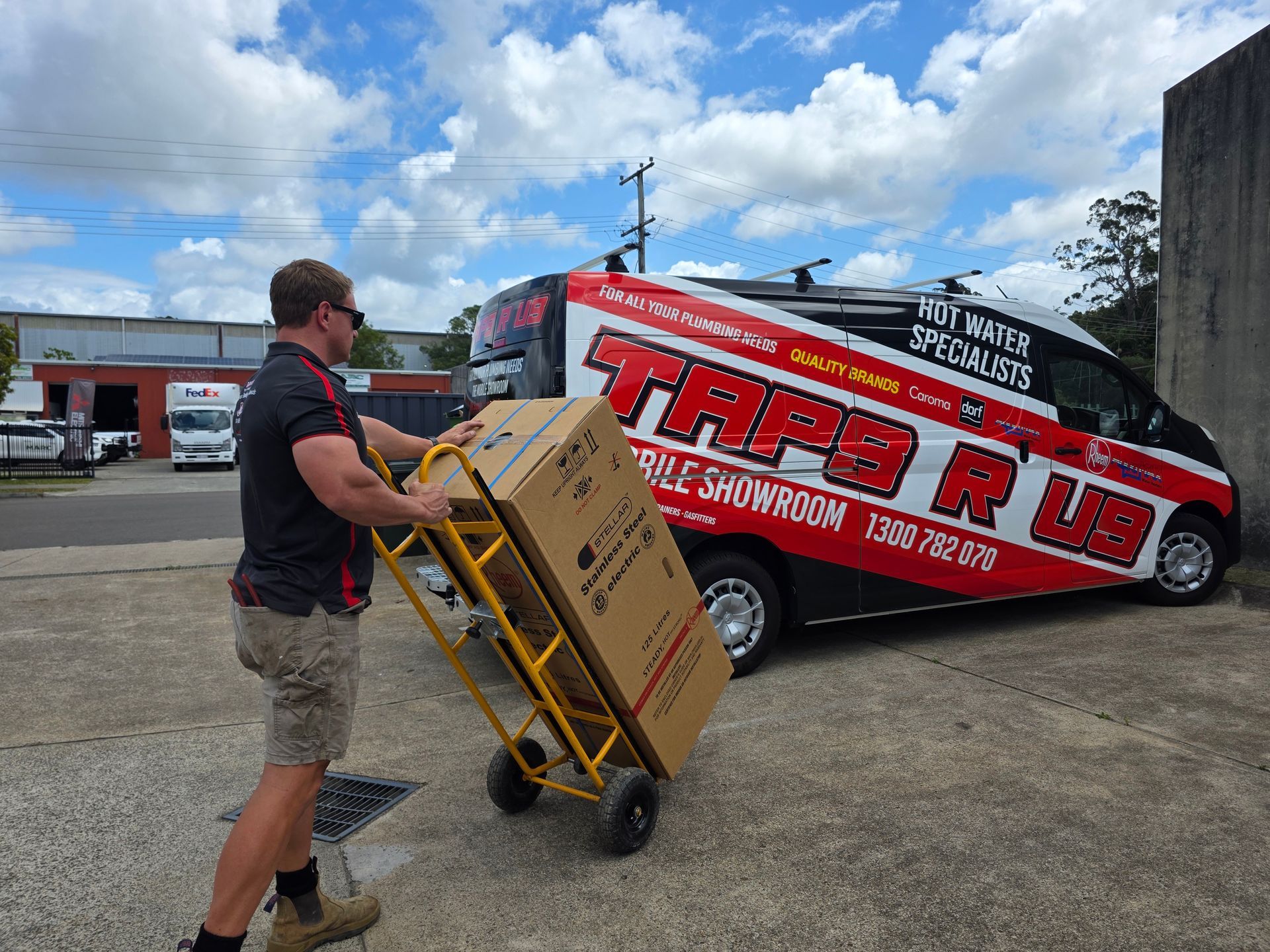 Man Loading Cardboard Boxes on A Yellow Hand Truck Beside a Red-And-Black — Taps 'R' Us in Alexandra Headlands, QLD