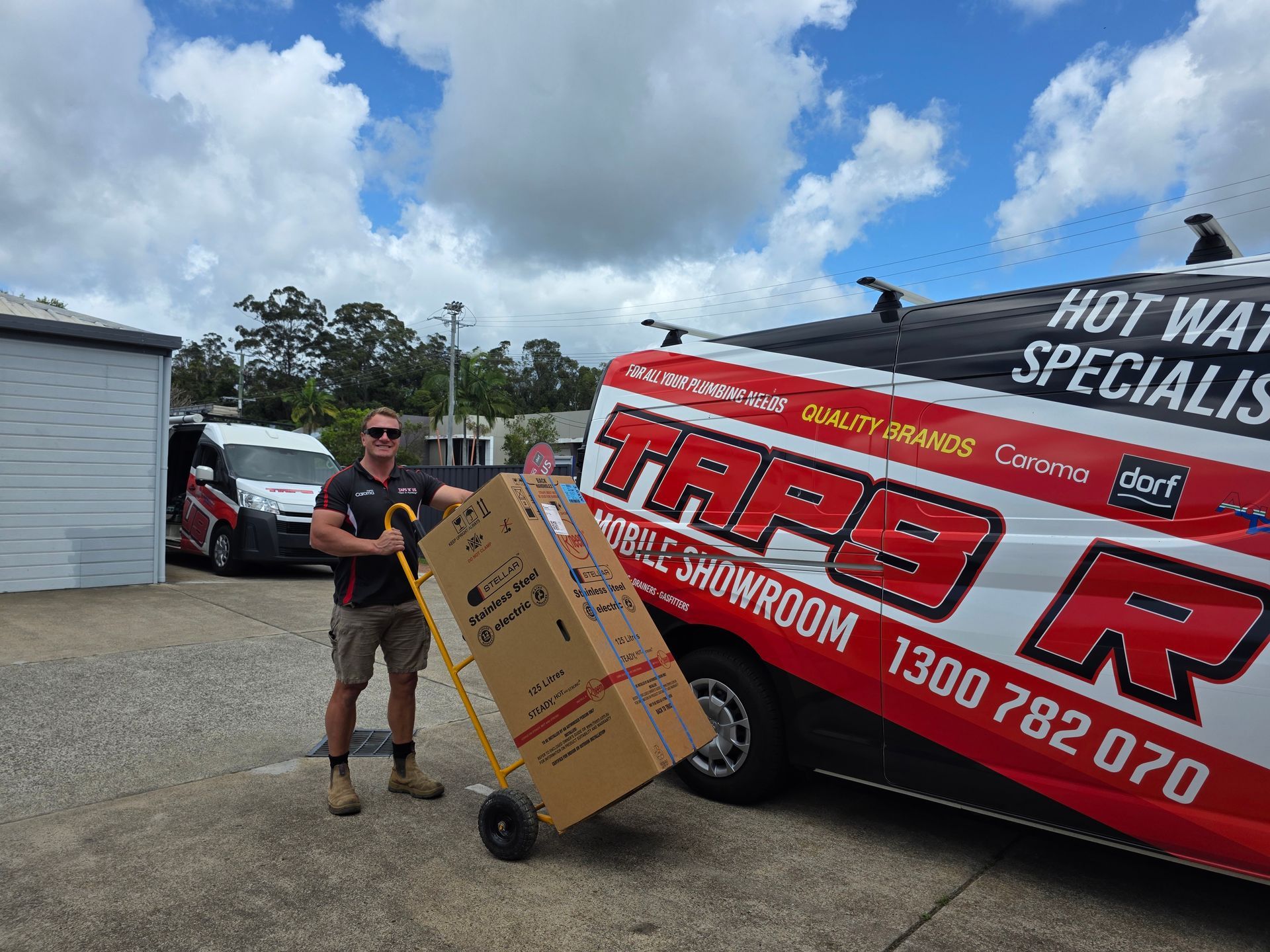 Man in Sunglasses Pushing a Large Cardboard Box Beside a Tapesr Van in A Driveway — Taps 'R' Us in Alexandra Headlands, QLD