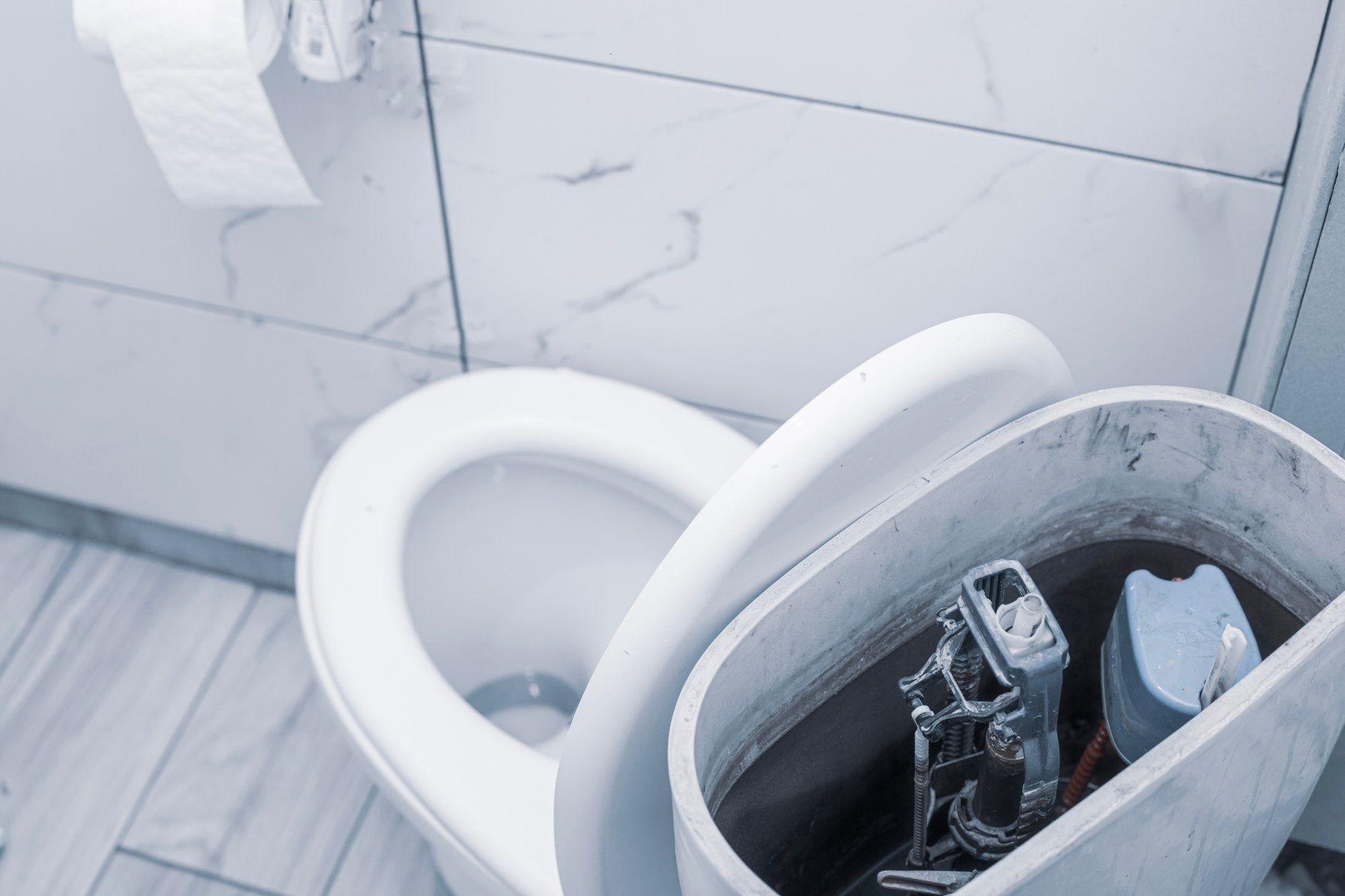 Toilet with the lid up, showing the internal mechanisms, in a bathroom with white marble tiles — Taps 'R' Us in Baringa, QLD