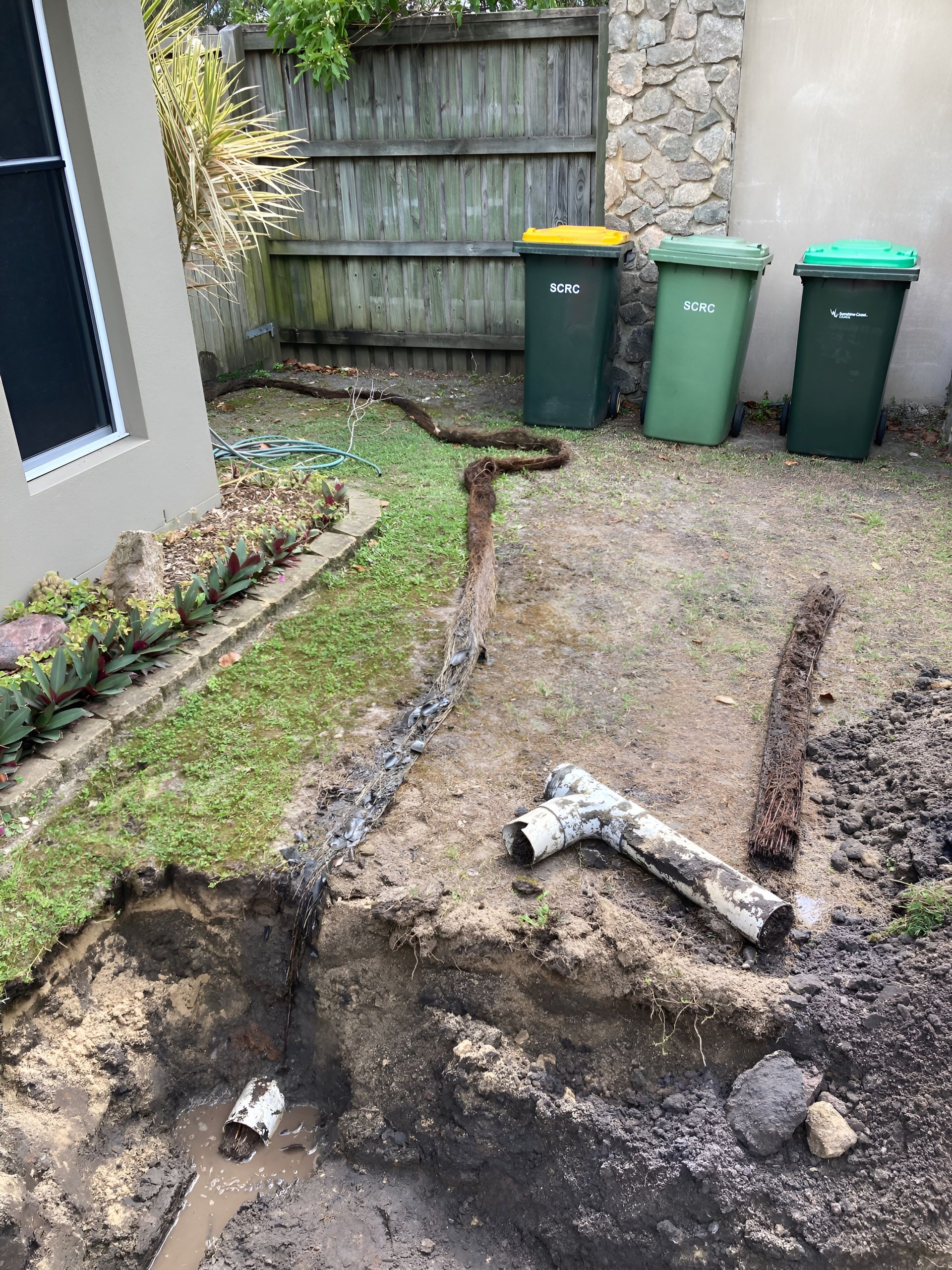 A Trench Dug in a Yard Near Trash Cans — Taps 'R' Us in Sippy Downs, QLD