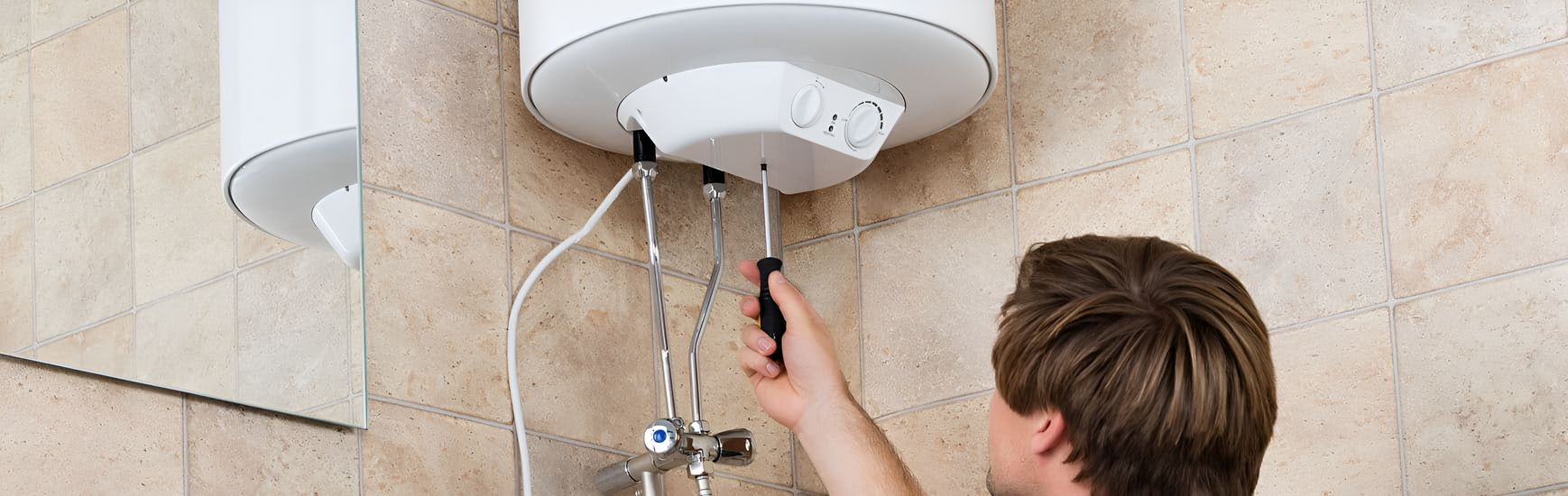 A Person Fixing a White Water Heater on a Beige Tiled Wall — Taps 'R' Us in Sippy Downs, QLD