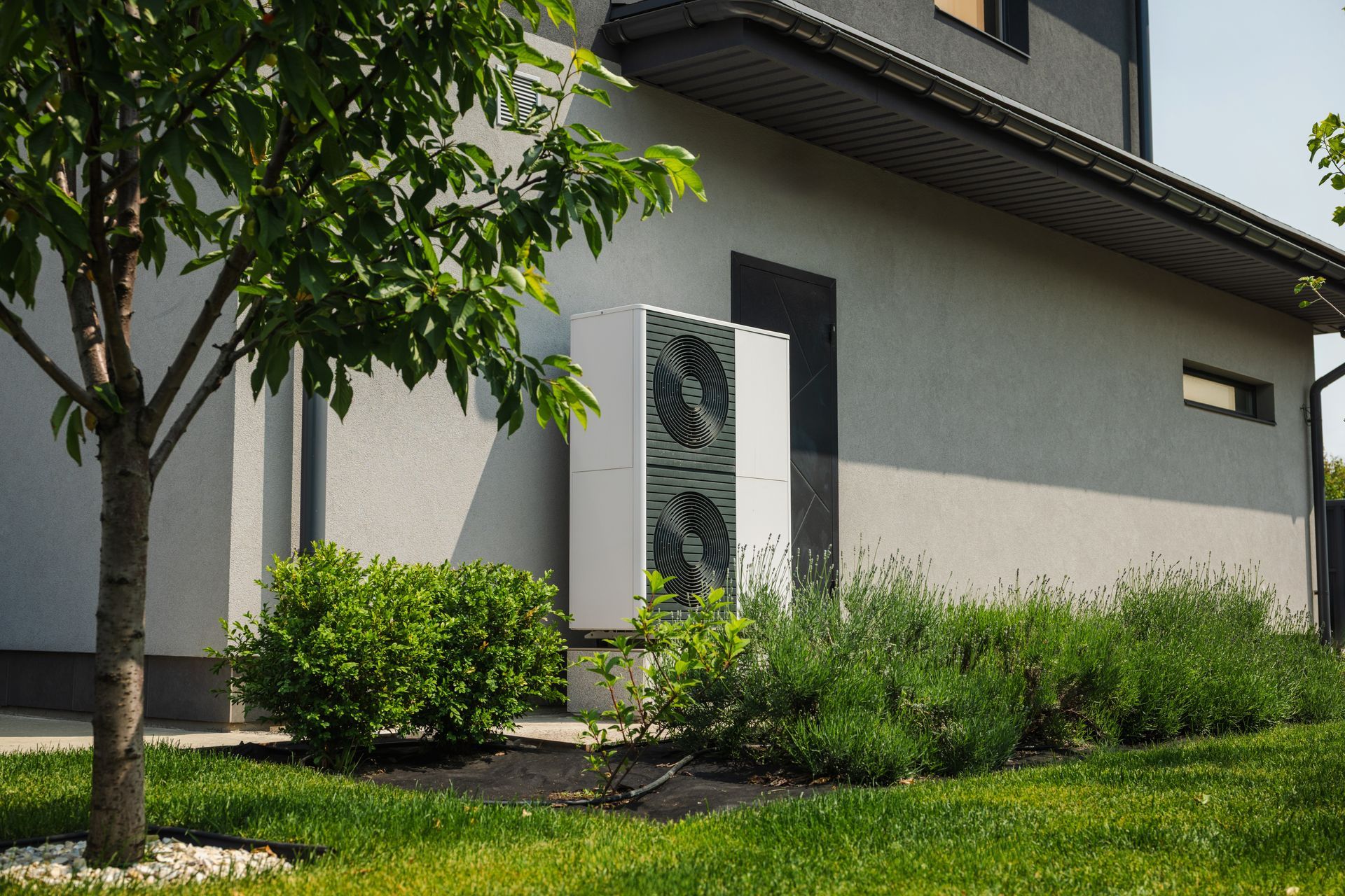 Air source heat pump installed outside a modern house with landscaped yard. — Taps 'R' Us in Kunda Park, QLD