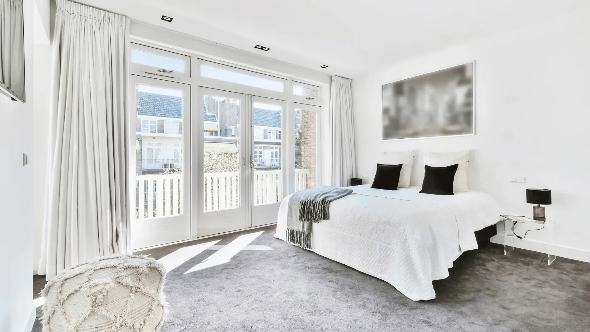 A bedroom with a large bed and a balcony.