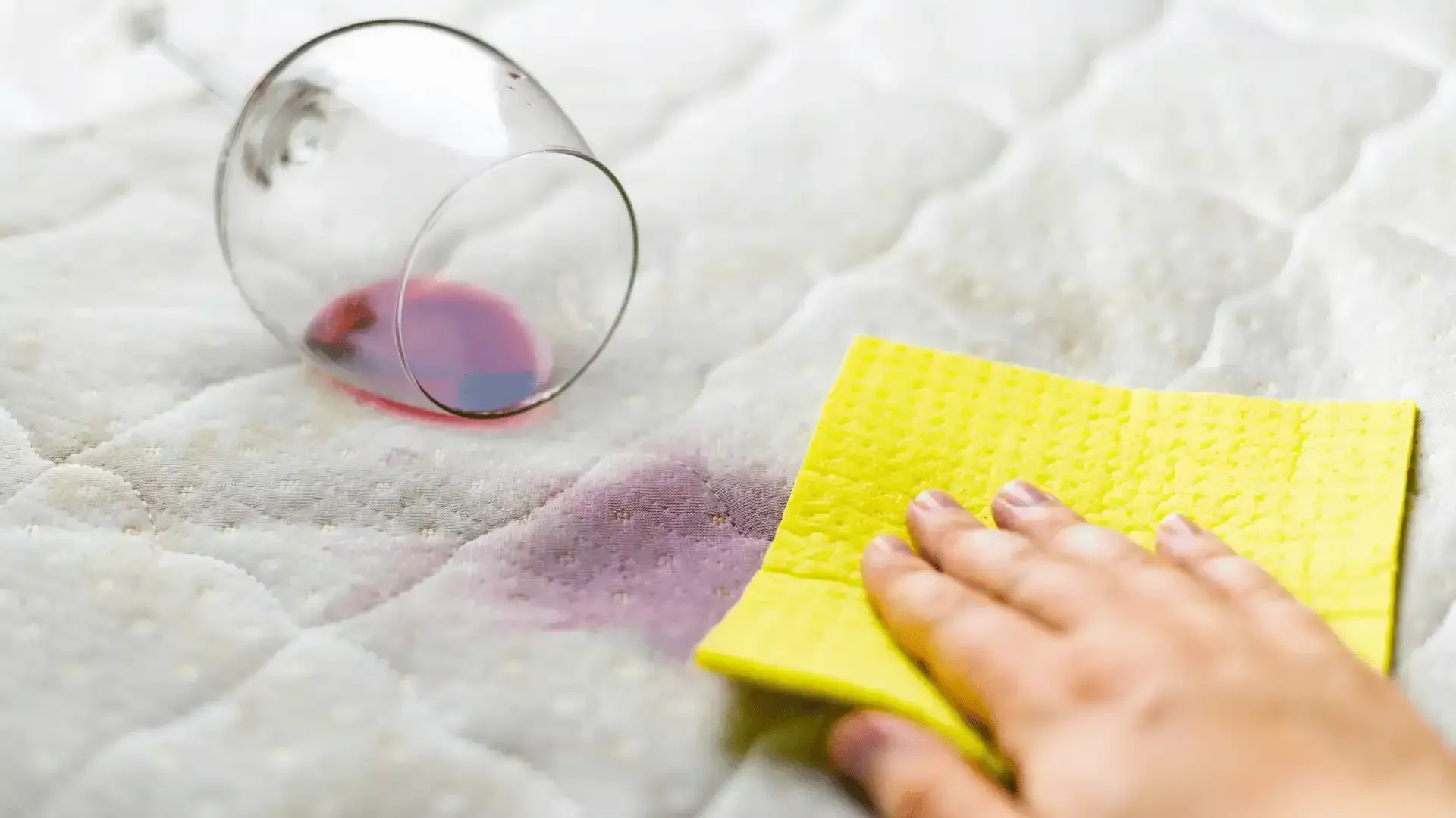 A person is cleaning a mattress with a yellow cloth.
