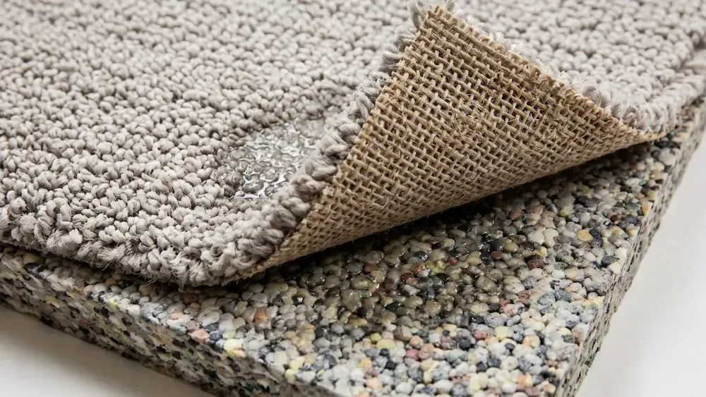 Stacked carpet samples with different textures and colors, one corner folded back to show the underside.