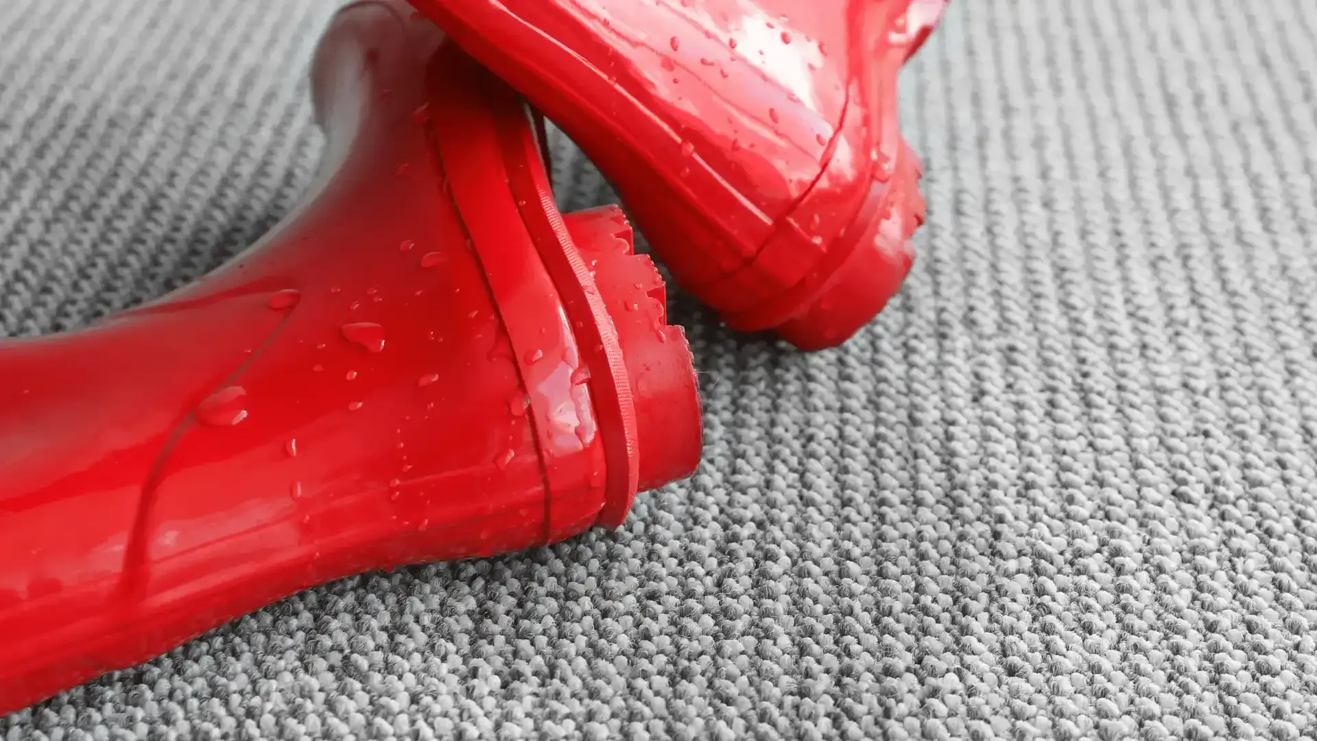 a pair of red rain boots are sitting on a carpet .