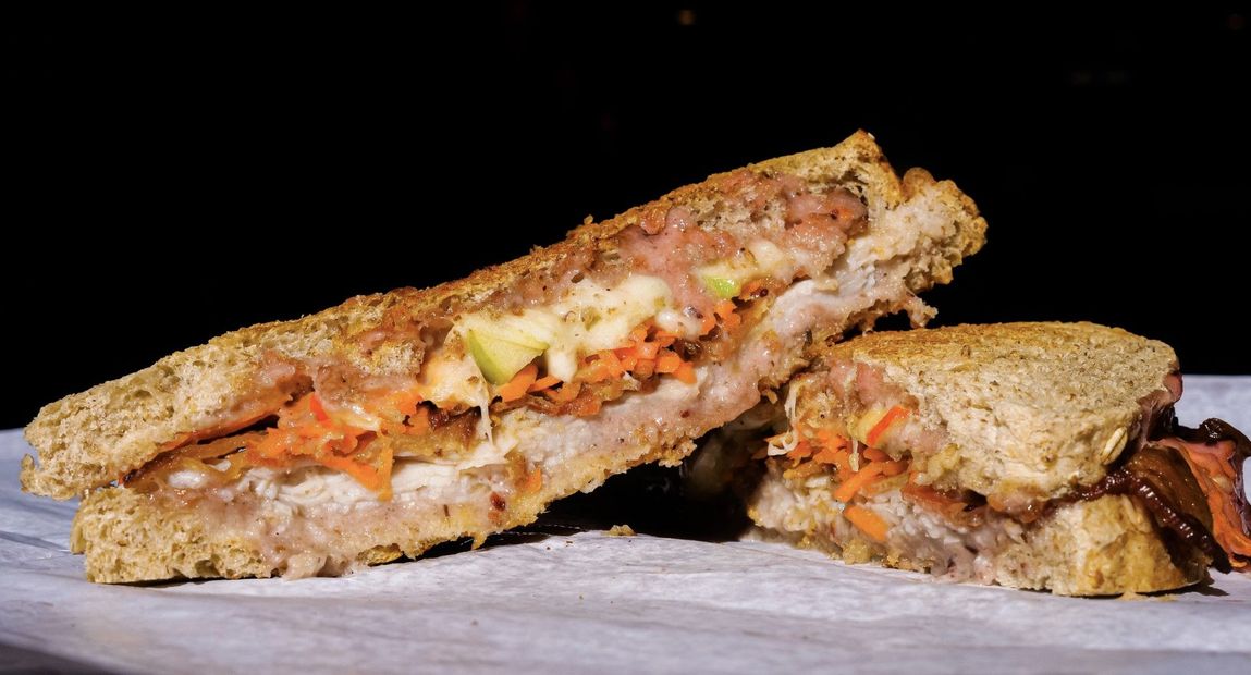 A person is holding a sandwich that has been cut in half.