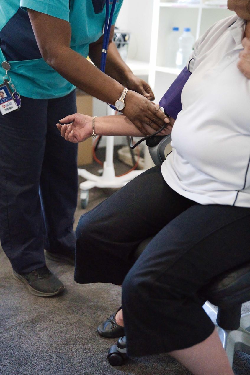 Person with white polo, having their blood pressure measured