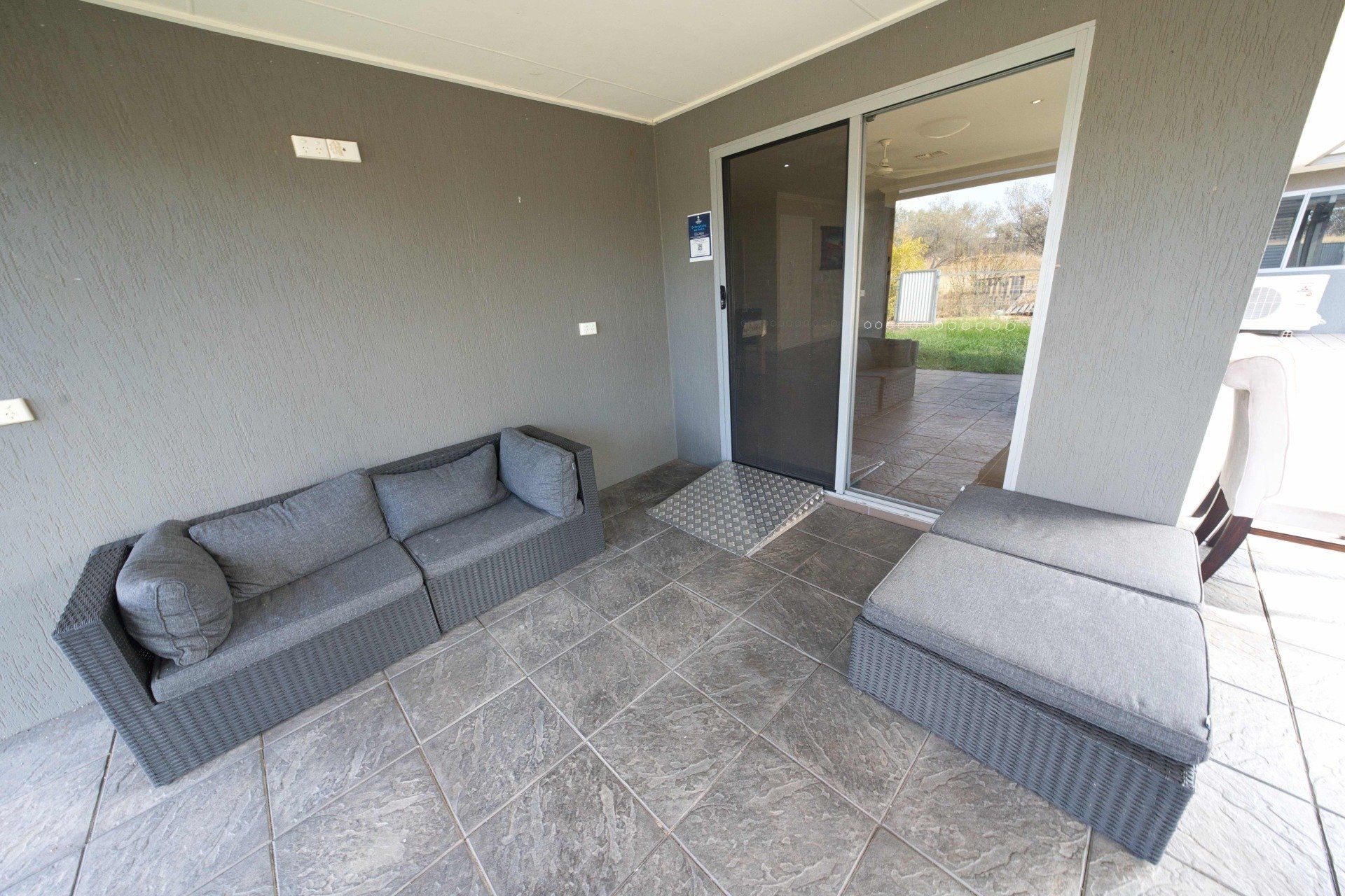 A patio with a couch and ottoman and a sliding glass door.