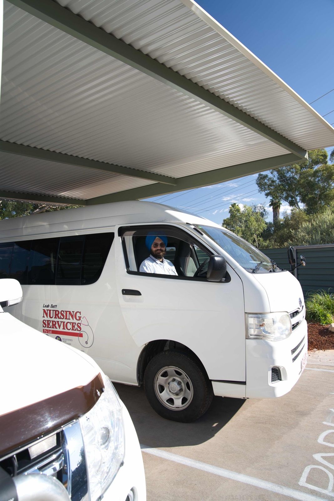 A man in a turban is driving a white van in a parking lot