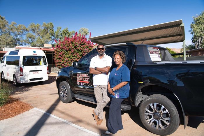 A man and a woman are standing next to a truck in a parking lot.