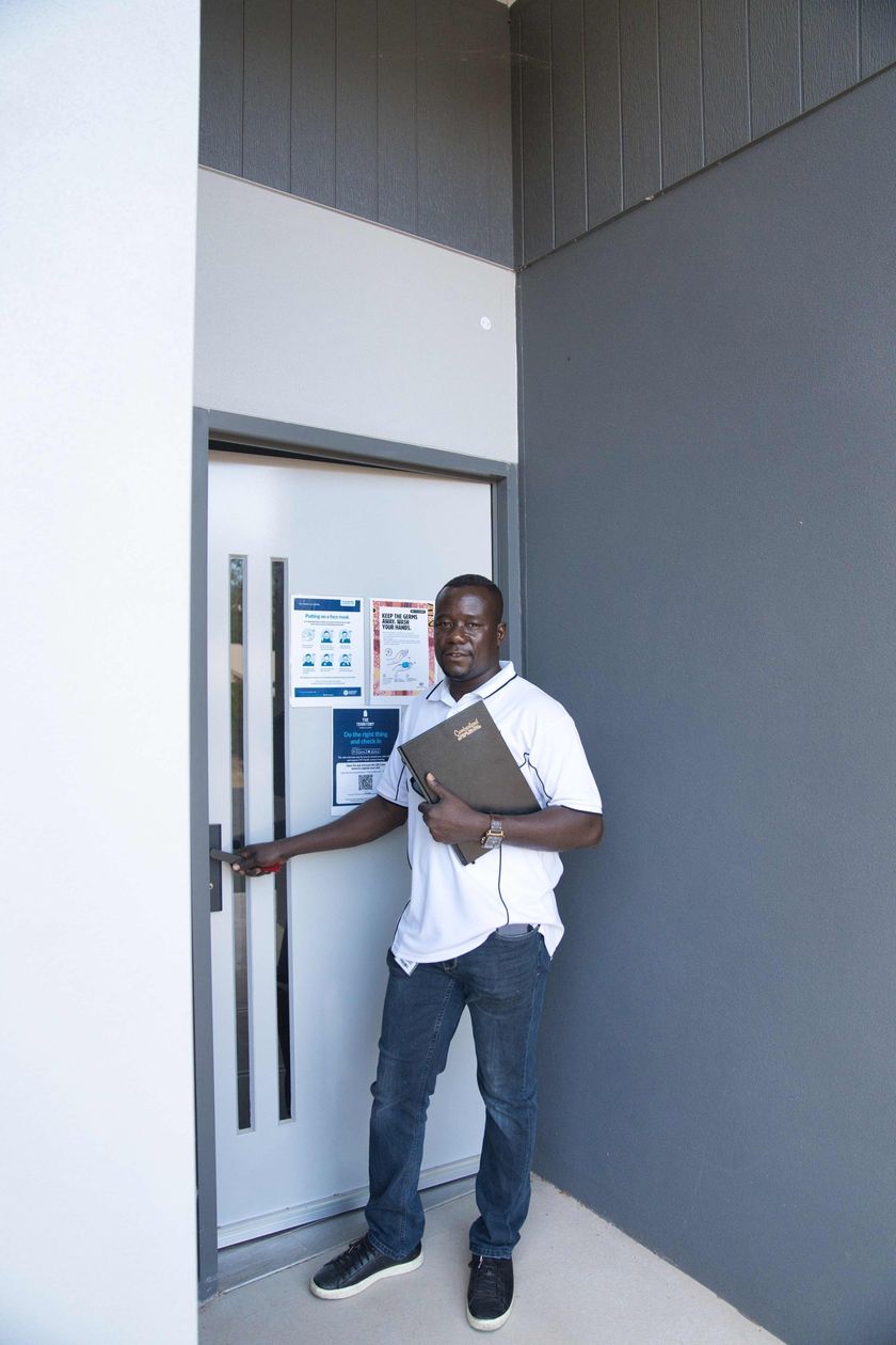 A man is standing in front of a door holding a folder.
