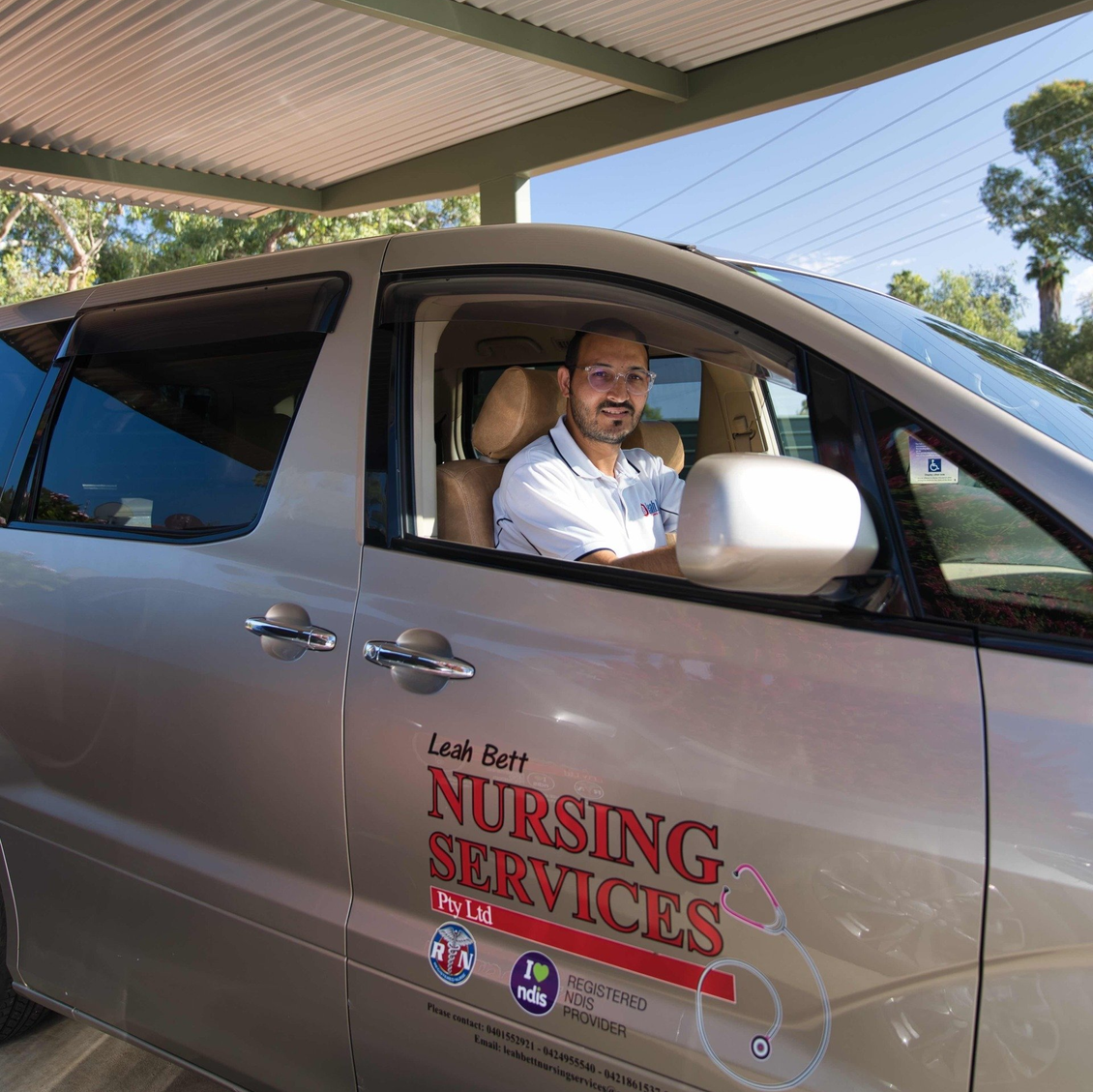 A man is sitting in the driver 's seat of a nursing services van