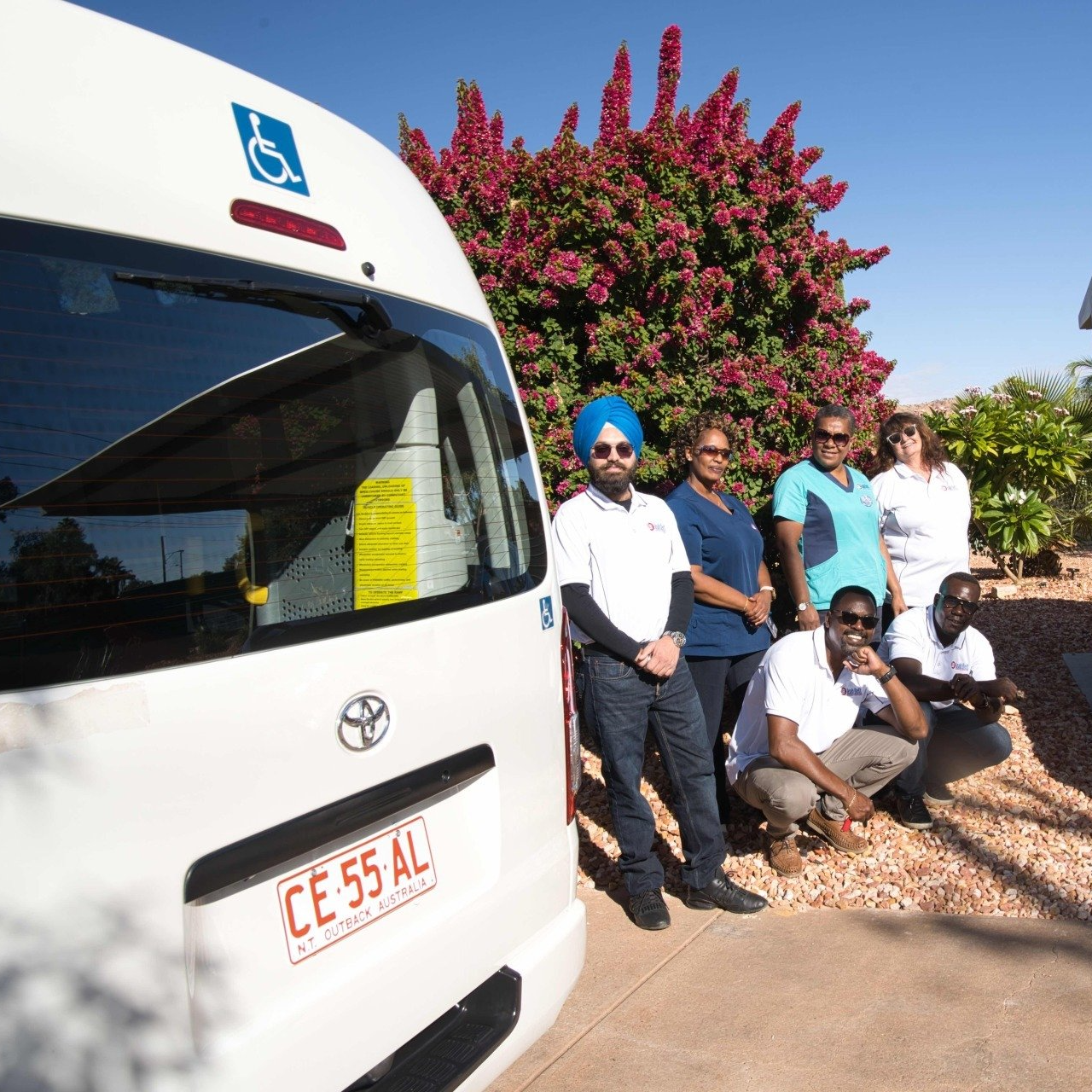 A group of people standing in front of a white van with a license plate that says ce-55 al