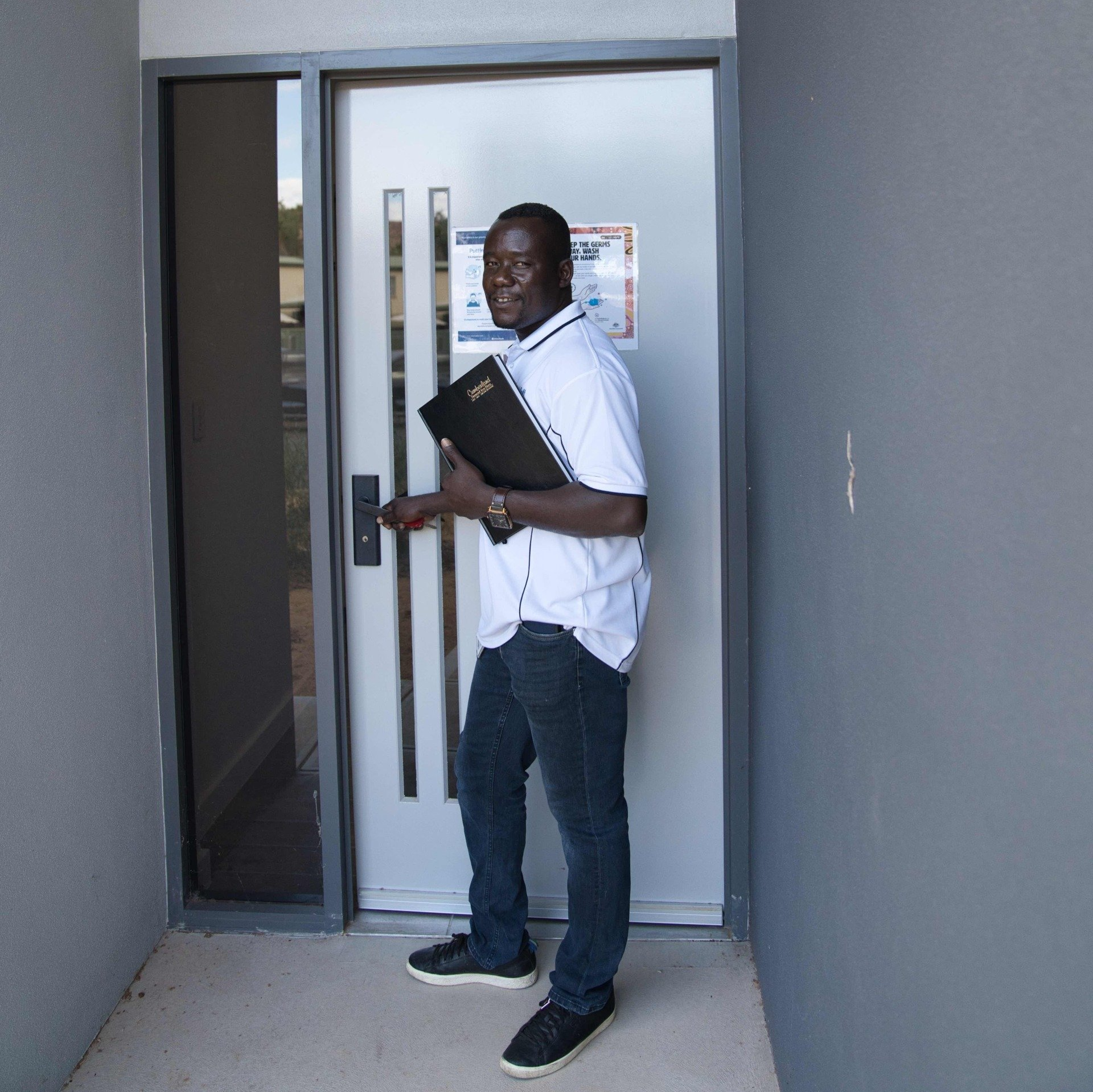 A man standing in front of a door holding a book