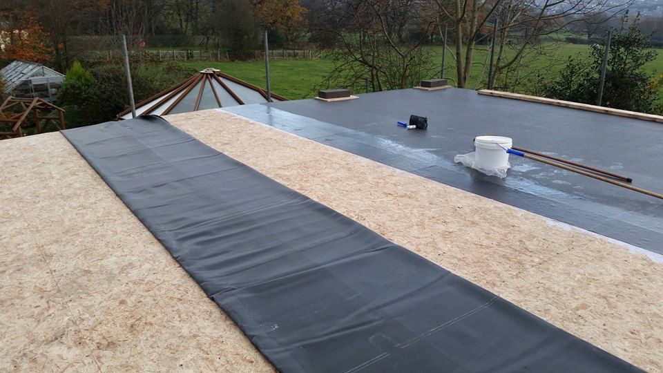 Rooftop under construction with black waterproof membrane and white roofing panels