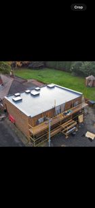 Aerial view of a house under construction with a white roof and wooden scaffolding around it.