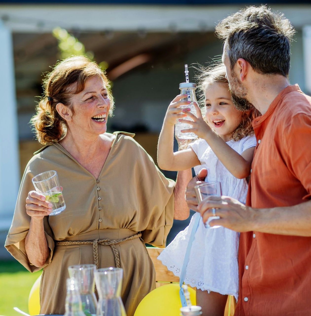 A group of people are standing around a table holding drinks.