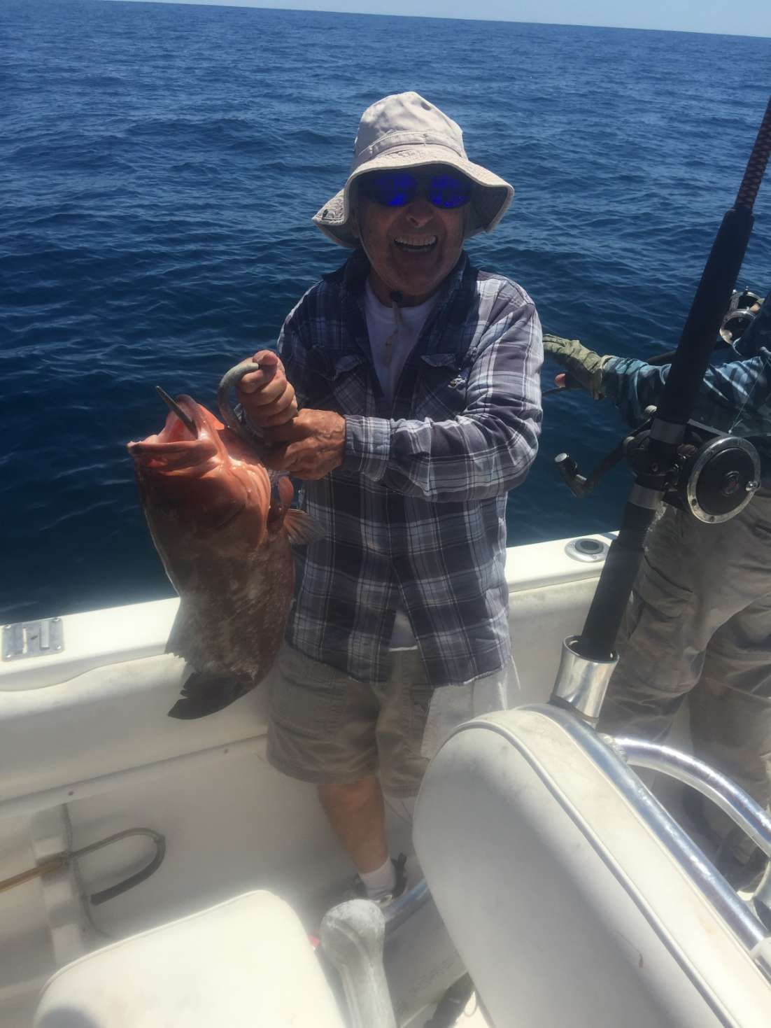 A man is holding a large fish on a boat in the ocean.
