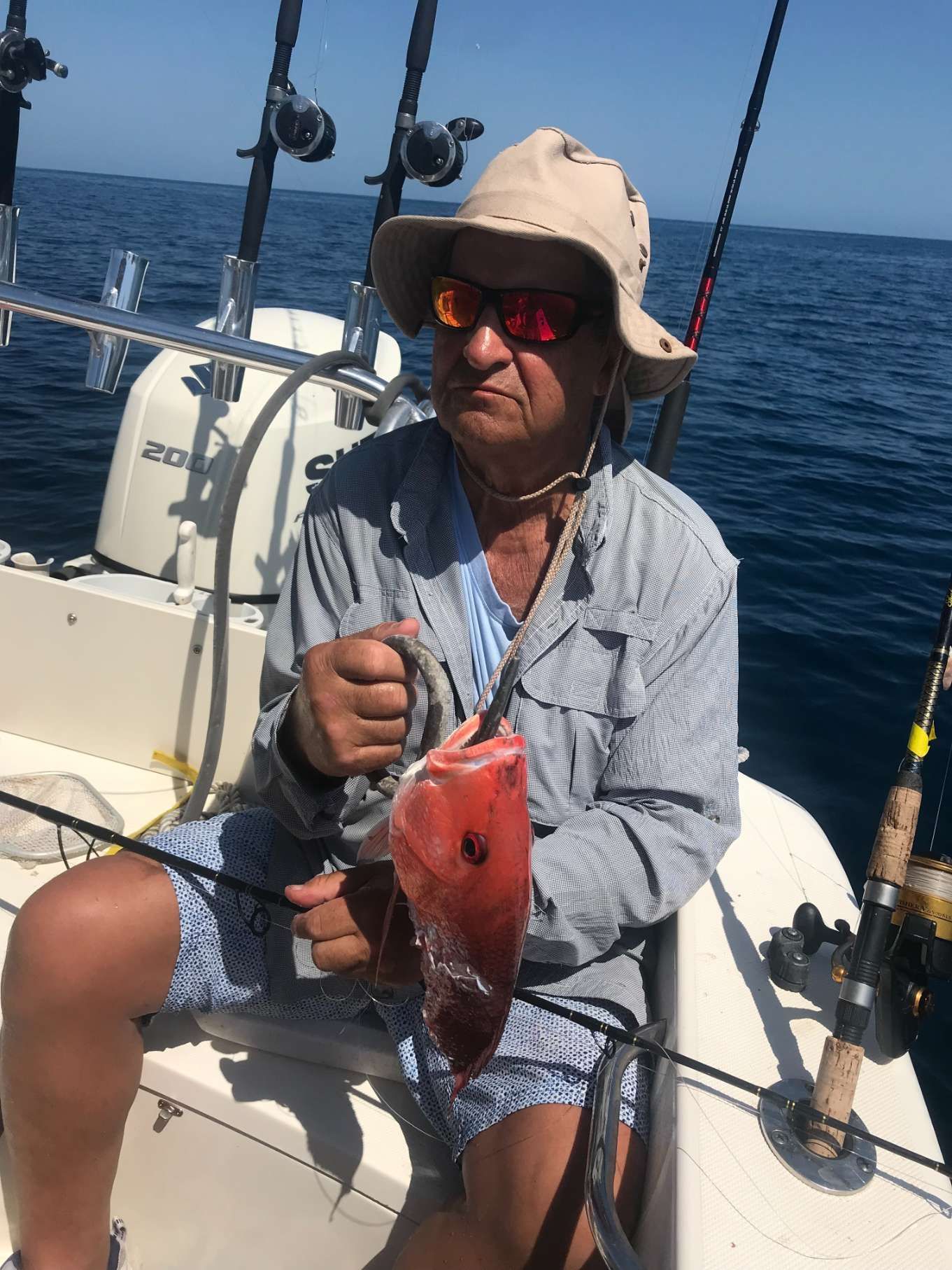 A man is sitting on a boat holding a fish.